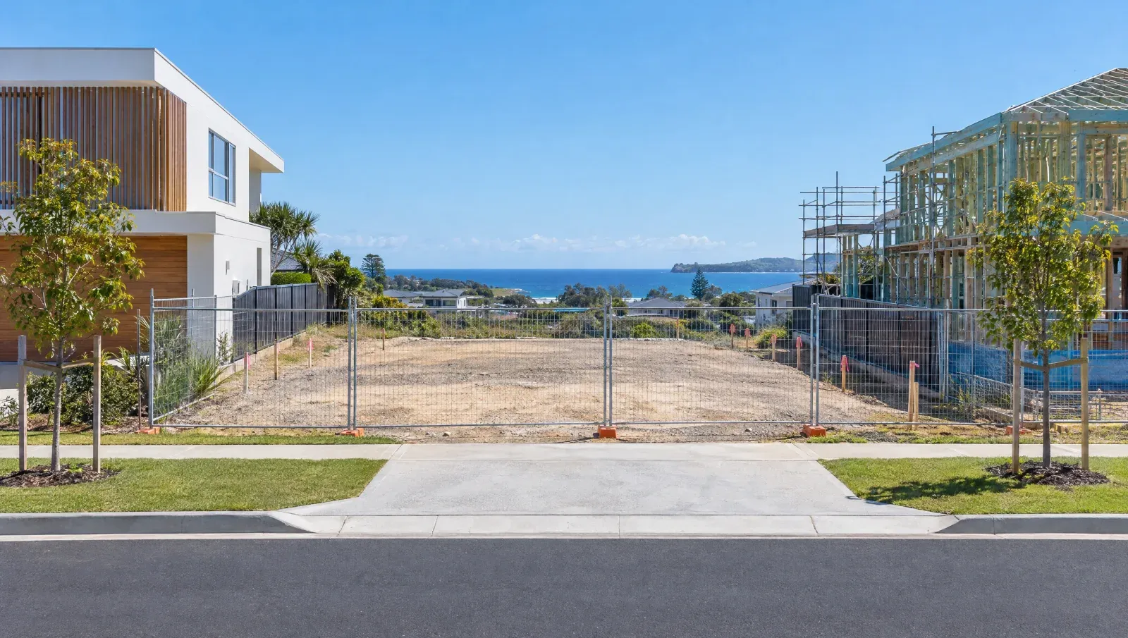 A cleared, pegged-out house block between two new homes
